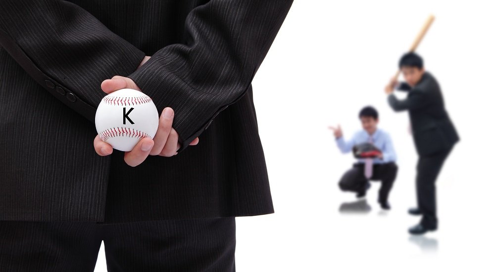 Business person holding a baseball behind his back and ready to pitch to a salesperson and catcher